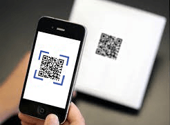 Phone scanning a QR code on a white surface.