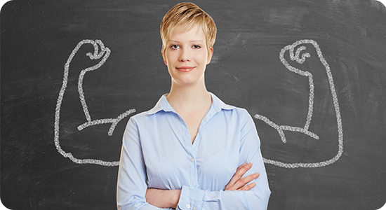 Confident woman standing in front of drawn flexed arms on chalkboard